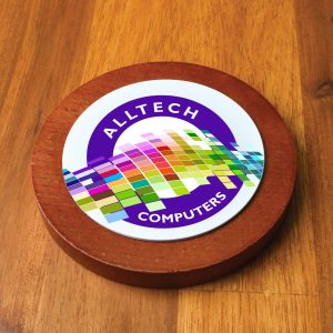 A round wooden coaster featuring a colorful logo with various geometric shapes and the text "Alltech Computers."