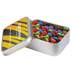 A silver rectangular tin filled with colorful M&M's, featuring a black and yellow design on the lid.