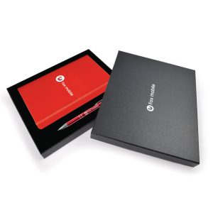 A gift set featuring a black box, a red notebook, and a red pen, all branded with the logo of Fox Mobile.