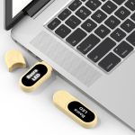 A wooden eco-friendly LED flash drive in light brown, partially inserted into a laptop's USB port, next to its cap.