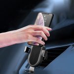A wireless car charger with a black mount, holding a smartphone, positioned on a car dashboard.