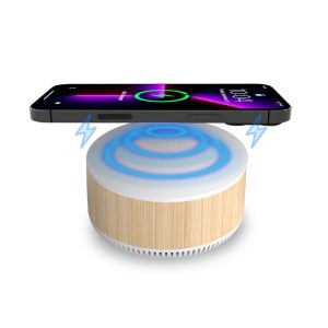 A bamboo-textured wireless charging speaker with a glowing blue top and a smartphone placed above it.
