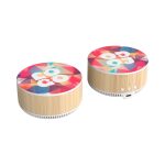 A wireless charging speaker with a colourful geometric design and a bamboo base. It features buttons and a charging port.