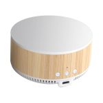 A round wireless charging speaker in a natural wood finish with a white top and control buttons on the front.