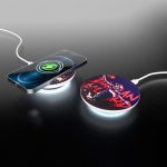 A round, wireless charger with a colourful design and a connected smartphone, featuring a glowing edge.