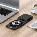 A black and grey Bellevue 3n1 magnetic wireless charger on a wooden desk beside a laptop and a coffee cup.