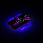 A wireless charger with a sleek acrylic design in purple, featuring a smartphone displayed on top, illuminated by soft light.