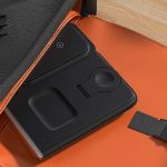 A black magnetic wireless charger and USB adaptor resting in an orange bag, showcasing its sleek design.