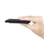 A black magnetic card wallet with a slim profile, being held in a hand against a white background.