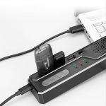 A black Akron Omnidirectional Speaker Phone connected to a laptop, featuring buttons and ports for connectivity.