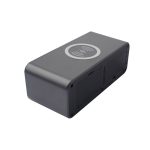 A black wireless charging speaker with a circular charging area on top and ventilation slots on the sides.