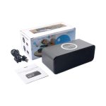 A black wireless charging speaker with a logo, accompanied by a USB cable and user manual, in its packaging.