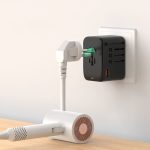 A black travel adaptor with multiple ports is plugged into a wall socket, connected to a white device.