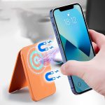An orange magnetic card wallet stand is being activated by a smartphone. The product features a sleek design with a logo.