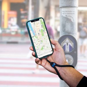 A hand holding a smartphone displaying a map, attached to a black eco-friendly wristband strap.