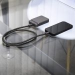A fast charge cable in black with a textured design, connected to a phone and a charging device on a glass surface.