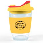 A reusable coffee cup with a clear base, yellow silicone sleeve, and red snap lid, featuring a logo.