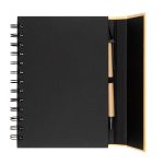 A black spiral-bound notebook with a pen positioned inside. The notebook has a smooth cover and a plain interior.