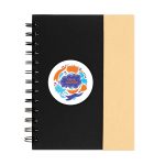 A black spiral-bound notebook with a tan cover and a circular logo on the front.