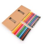 A pencil and crayon set with various colors arranged next to a brown cardboard box featuring two windows.