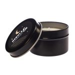 A black tin candle with an open lid, featuring a decorative label that includes stars and a crescent moon design.