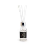 A vanilla reed diffuser in a transparent glass bottle with a black label and four white reeds.