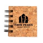 A cork notebook featuring a black spiral binding and the logo for "Twin Peaks Guest House" embossed on the cover.