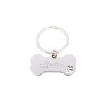 A silver dog bone keytag featuring a paw print design and an engraved logo.