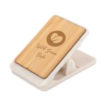 A magnetic clip with a bamboo surface and a white base, featuring a logo and a decorative design.