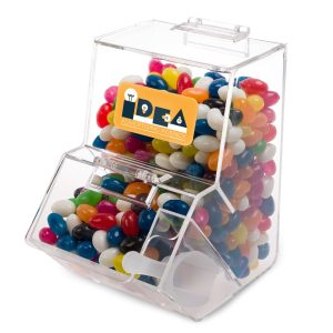 A clear dispenser filled with assorted color mini jelly beans. The dispenser features an advertising label.