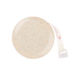 A beige tape measure made from wheat fibre, featuring a retractable measuring tape. It has a small branding logo.