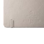 A recycled milk carton notebook with a textured grey cover and elastic band closure. It features branding on the back.