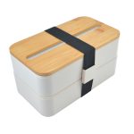 A two-tier eco lunch box in light grey with a bamboo lid and a black strap for secure closure. Includes a logo.