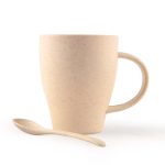 A drink cup in light beige with a handle and a matching spoon, made of wheat fibre material.