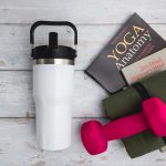 A drink bottle with a sleek white body and stainless steel accents, featuring a black lid and handle.