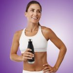A drink bottle in matte black with a metal lid, held by a smiling woman in a white athletic top.