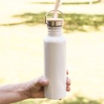A drink bottle made of recycled aluminum, featuring a sleek white finish and a wooden lid with a metal handle.