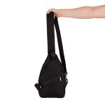 A black shoulder bag with a single strap, featuring a zippered pocket and a hand holding it.
