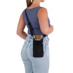 A black neck pouch is worn on a woman's back, featuring a strap and a logo. The woman is in fitted jeans and a tank top.