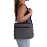 A grey cooler bag with a shoulder strap, featuring a front pocket and branding, carried by a person.