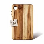 Acacia serving board with a natural wood finish, featuring a hole for hanging and a tag with branding.