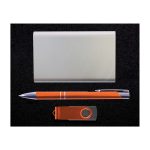 A gift set featuring a sleek silver card holder, an orange pen, and an orange USB flash drive.