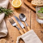 A cutlery set featuring a fork, knife, and spoon with wooden handles, packaged in a cloth pouch.