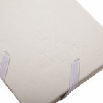A cream-coloured planner with an elastic band closure and embossed branding on the cover.