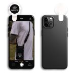 A black smartphone is displayed with an attached LED selfie light. The phone has a photo of a person wearing a bag.