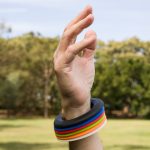 A hand wearing a wrist disc silicone flyer with colorful, flexible rings stacked on the wrist.