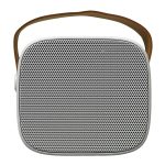 A compact speaker with a square design and mesh front, featuring a brown carrying strap.