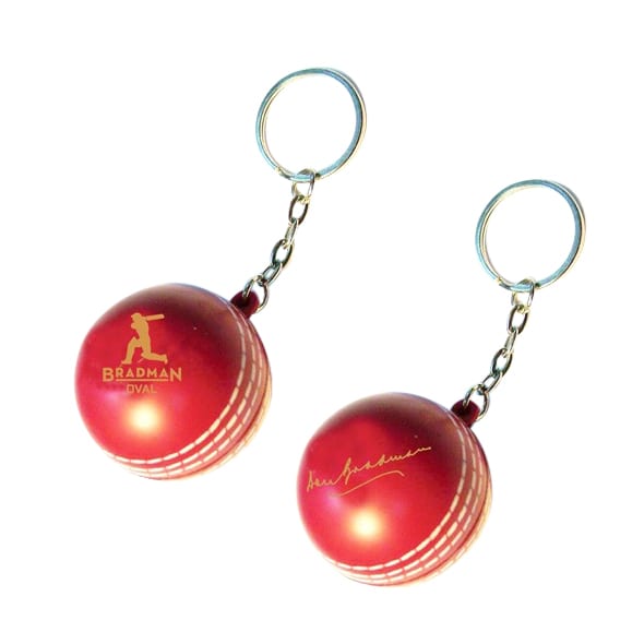 A red keyring featuring a cricket ball stress reliever, with a silver keychain and a logo. Keyring with Cricket Ball Stress Reliever - Image 1