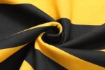 A close-up of folded fabric featuring bold black and yellow stripes, showcasing its texture and pattern.