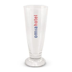 A clear beer glass with a tall, slender design and a base, featuring a logo in red and blue.